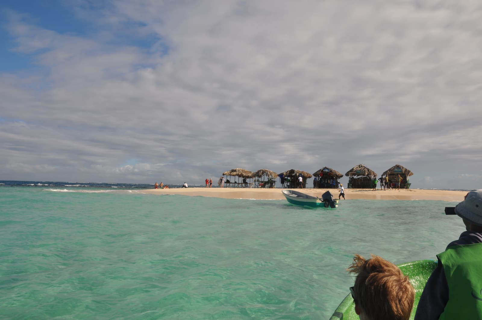 The sandbar of Cayo Arena (Paradise Island) with thatched shelters and a boat in turquoise water