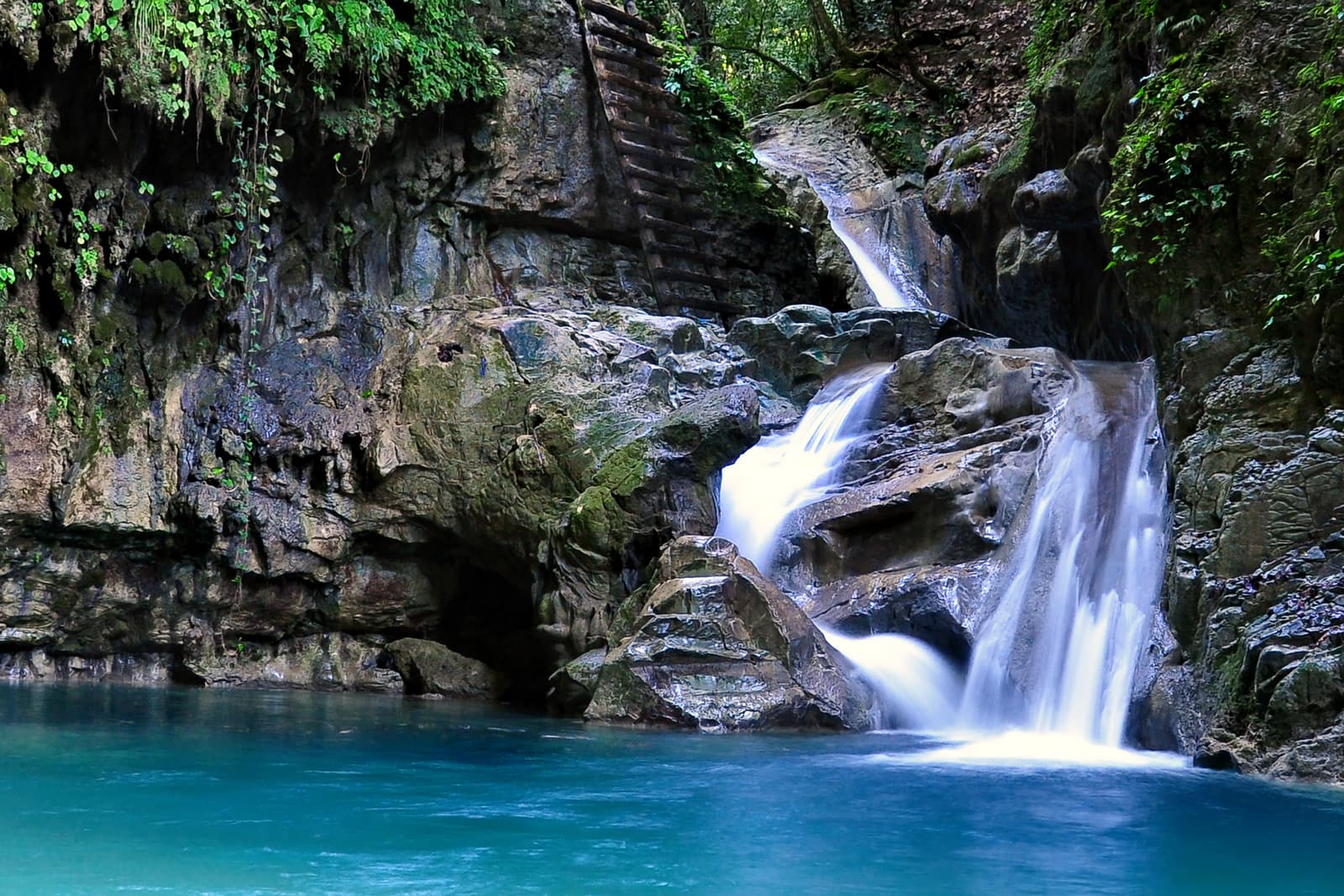 A waterfall pouring into a turquoise pool at the 27 Charcos de Damajagua near Puerto Plata