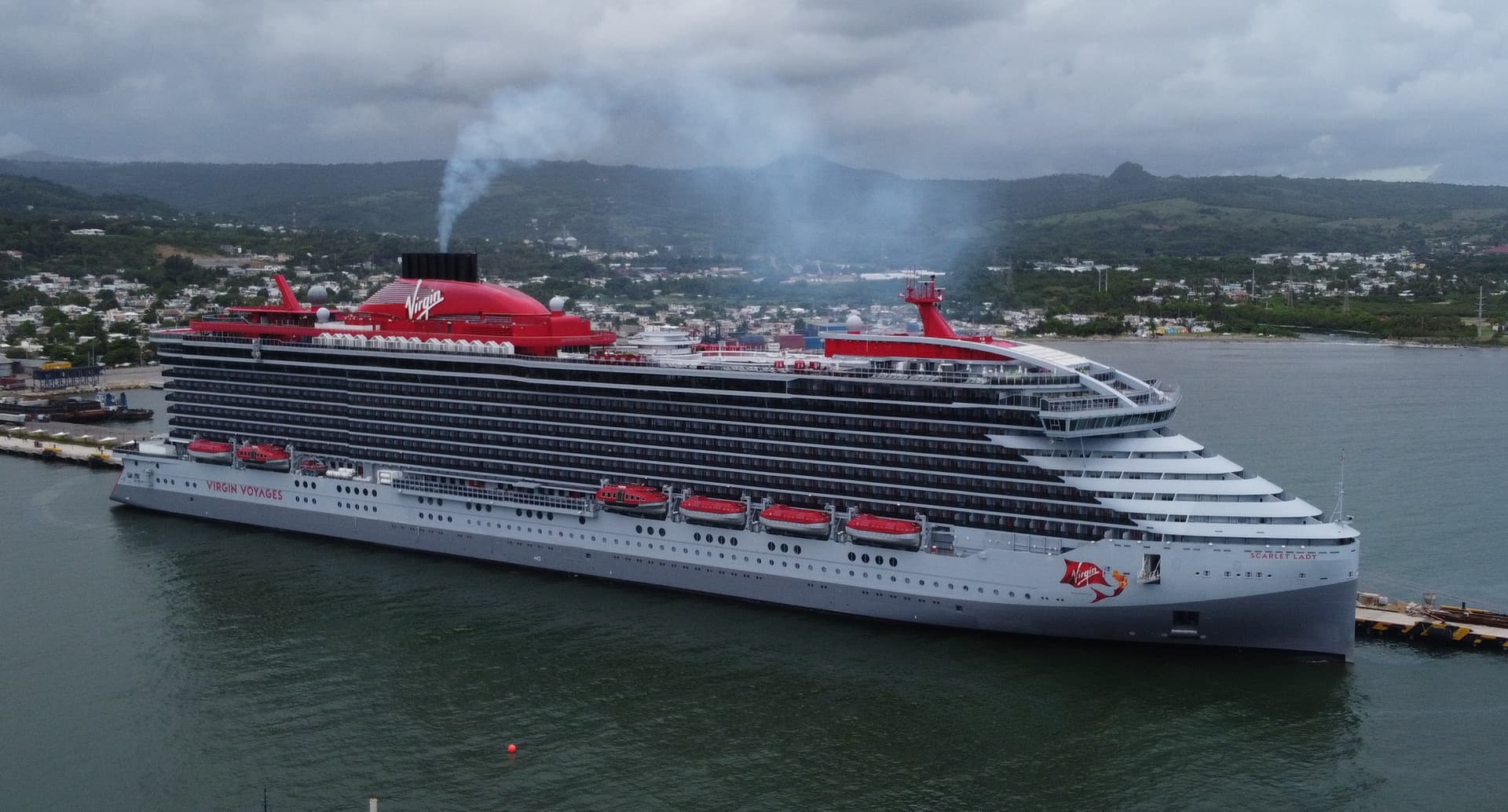 A cruise ship moored at the Taino Bay pier with Puerto Plata and green hills behind