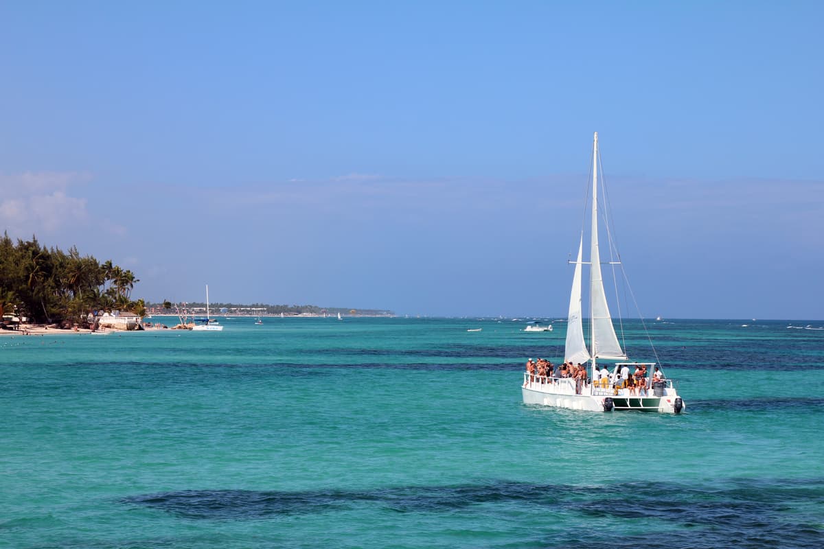 A sailing catamaran with passengers on turquoise water off the Dominican coast