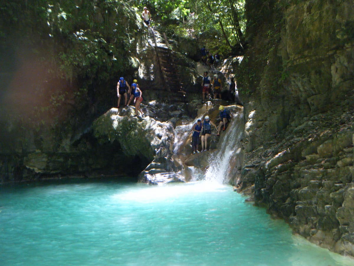A turquoise pool below a small waterfall at the 27 Charcos de Damajagua